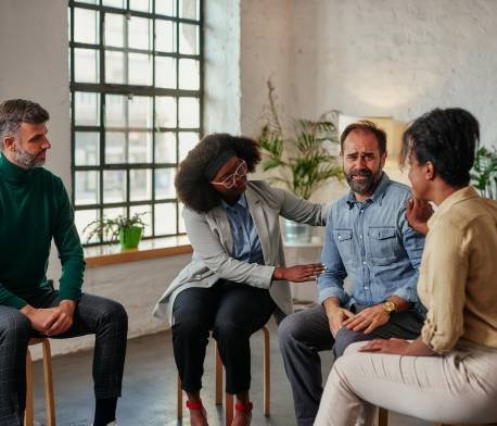 Un grupo de personas sentadas en sillas en una habitación, participando en una discusión.