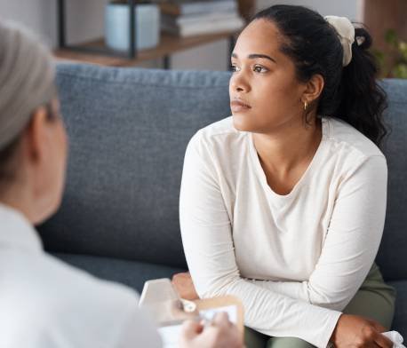 Mujer discutiendo preocupaciones con un psicólogo en un entorno clínico.